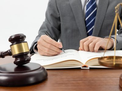 closeup-shot-person-writing-book-with-gavel-table